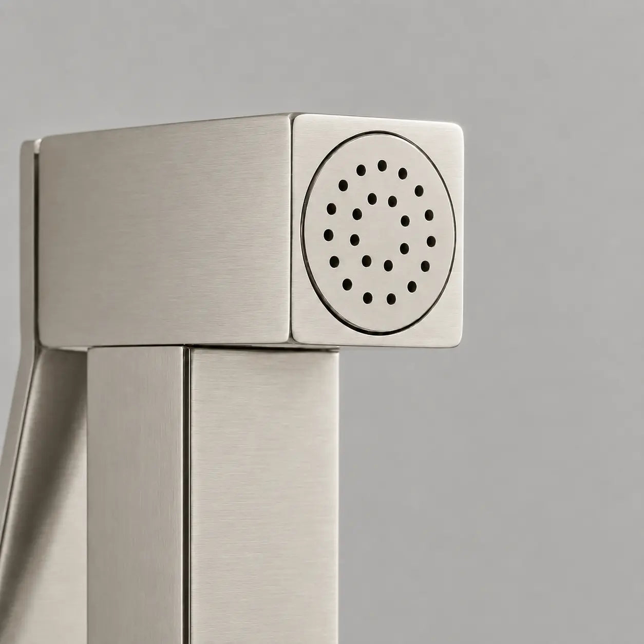 Gros plan sur la tête de douchette WC gris brossé, design carré moderne avec buses de pulvérisation intégrées. Image
