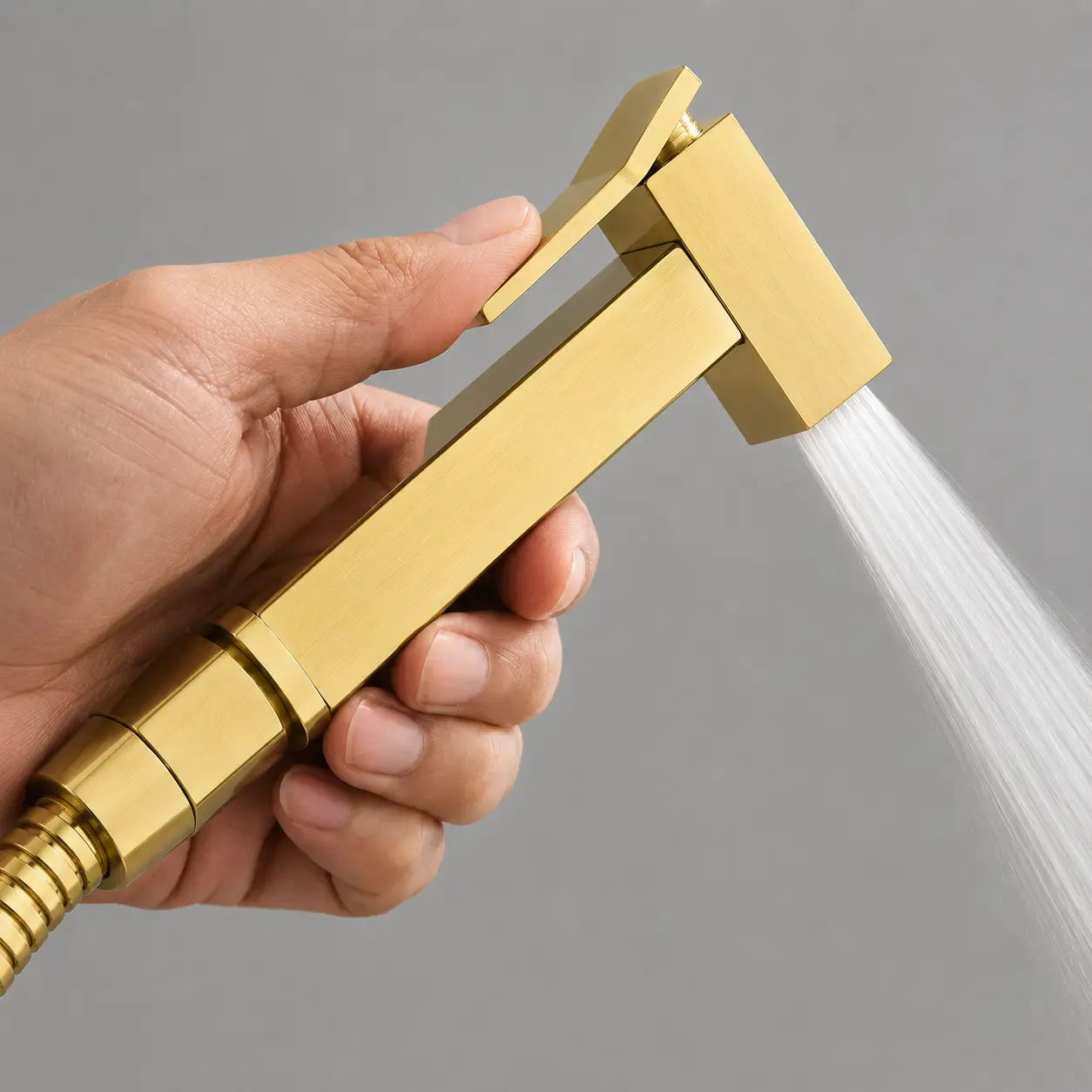 Douchette WC or brossé en fonctionnement avec gâchette ergonomique et jet d’eau précis pour une hygiène optimale. Image