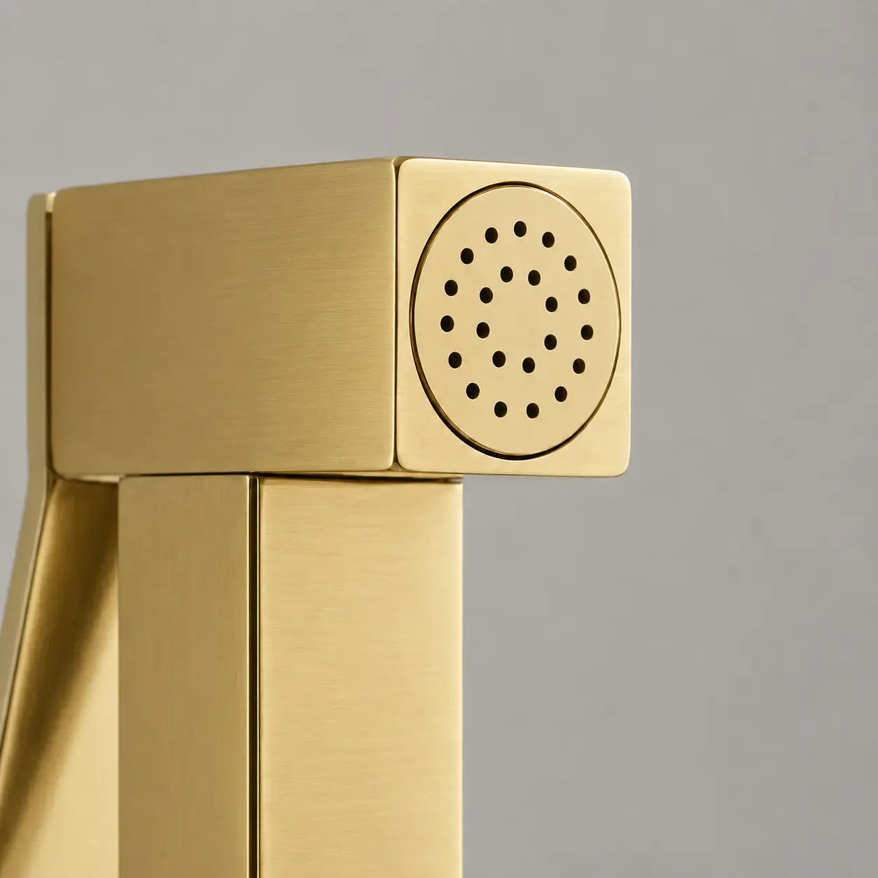 Gros plan sur la tête de douchette WC en or brossé avec buses de pulvérisation précises et design carré moderne. Image