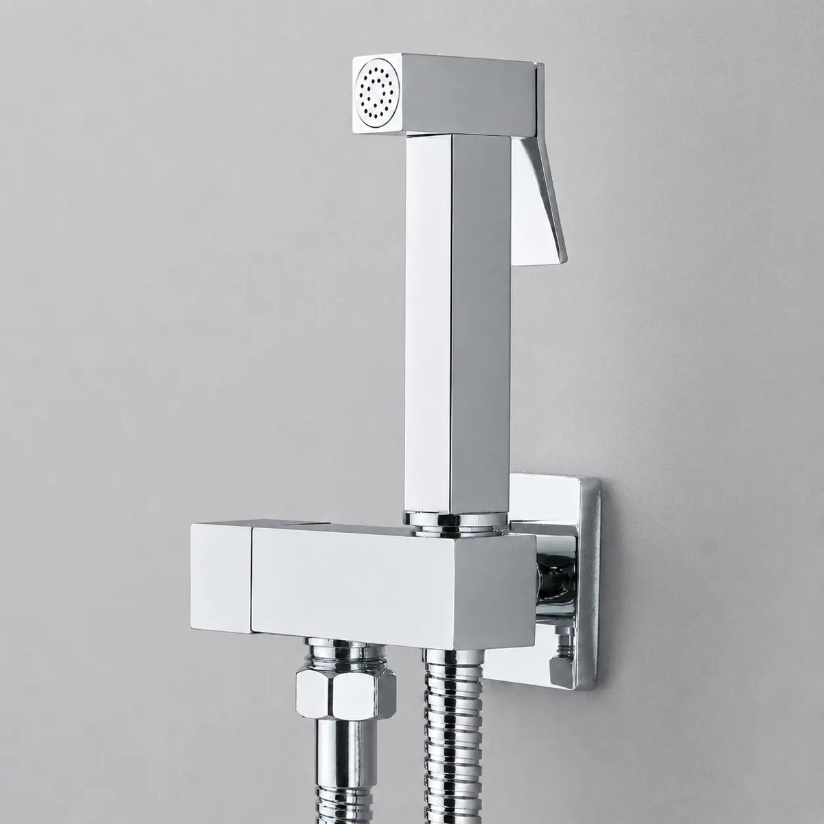 Douchette hygiénique WC chromée avec design carré moderne, flexible inox et commande ergonomique murale.