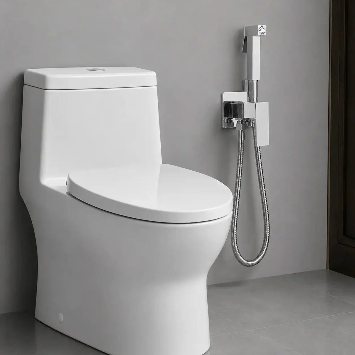 Douchette WC hygiénique chromée installée près des toilettes avec flexible inox et support mural au design carré moderne.