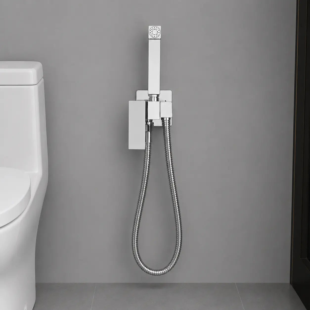 Douchette WC hygiénique chromée avec support mural intégré et flexible inox, installée à côté des toilettes Image