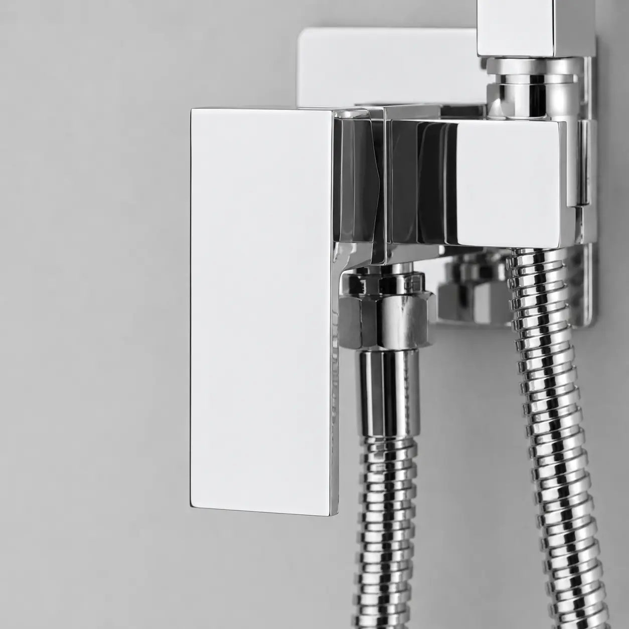 Gros plan sur le mitigeur chromé d’une douchette WC hygiénique avec flexible inox et design carré moderne. Image