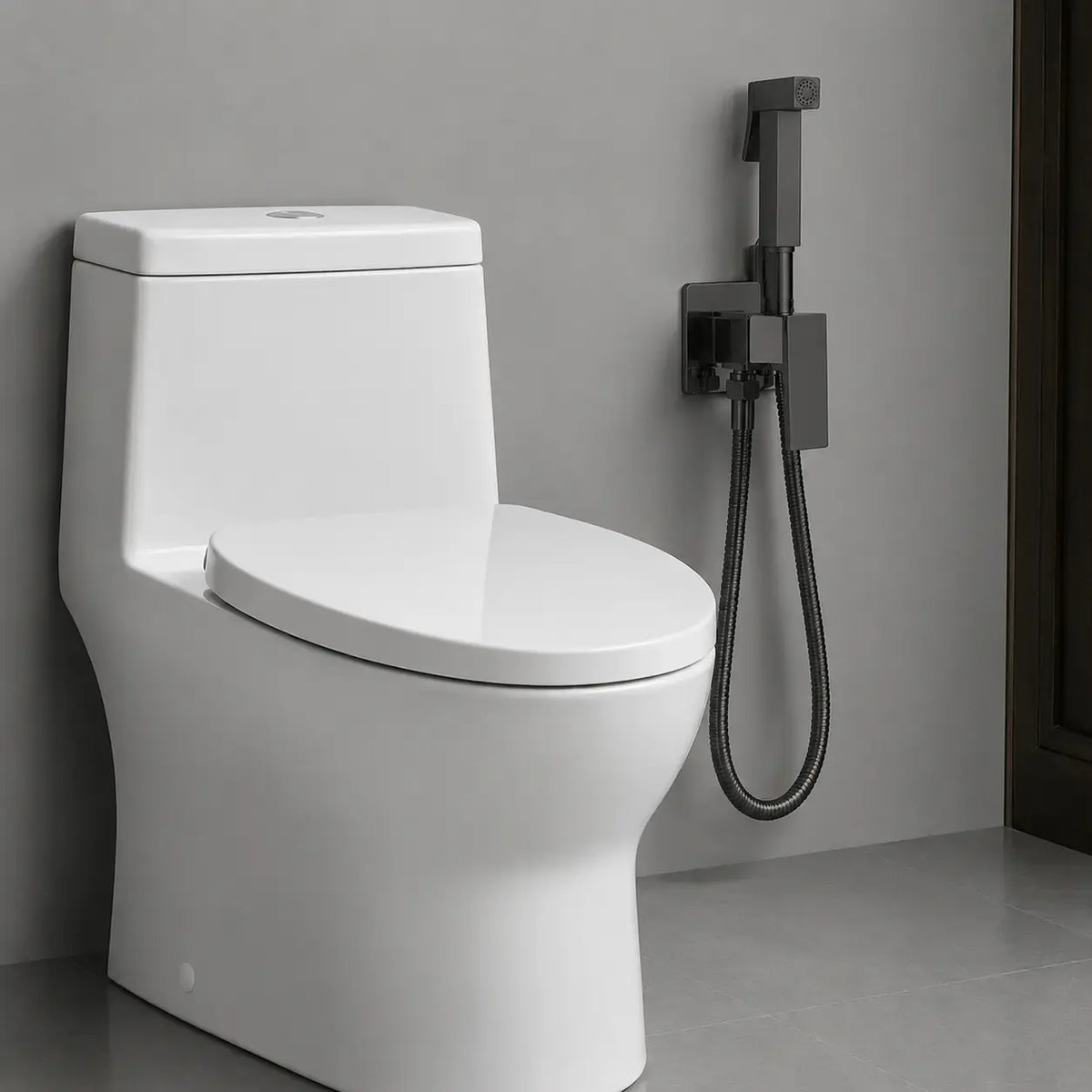 Douchette hygiénique WC noir mat installée à côté d’un toilette moderne, avec support mural et flexible assorti.