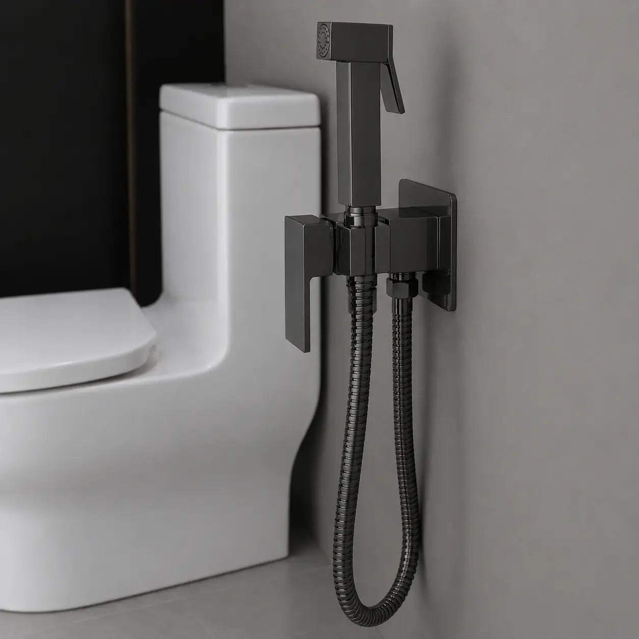 Douchette WC hygiénique noir mat avec mitigeur intégré, support mural et flexible métallique, installée à côté des toilettes. Image