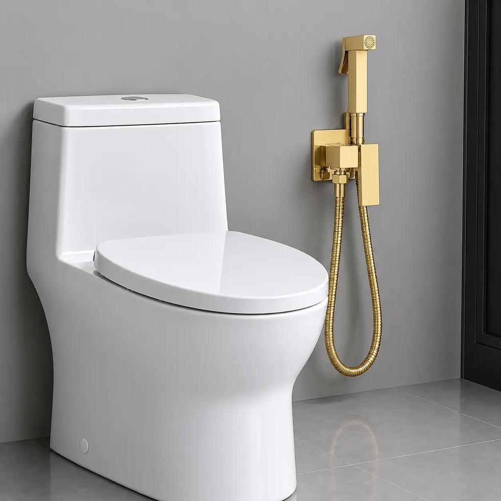 Douchette WC hygiénique or brossé fixée au mur à côté d’un WC blanc moderne, avec flexible métallique et support assorti.