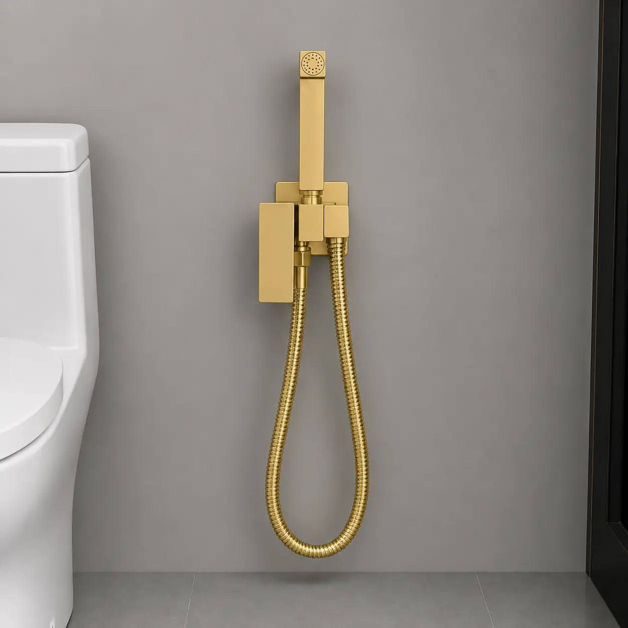 Douchette hygiénique WC en or brossé avec support mural intégré et flexible métallique, installée sur un mur moderne. Image