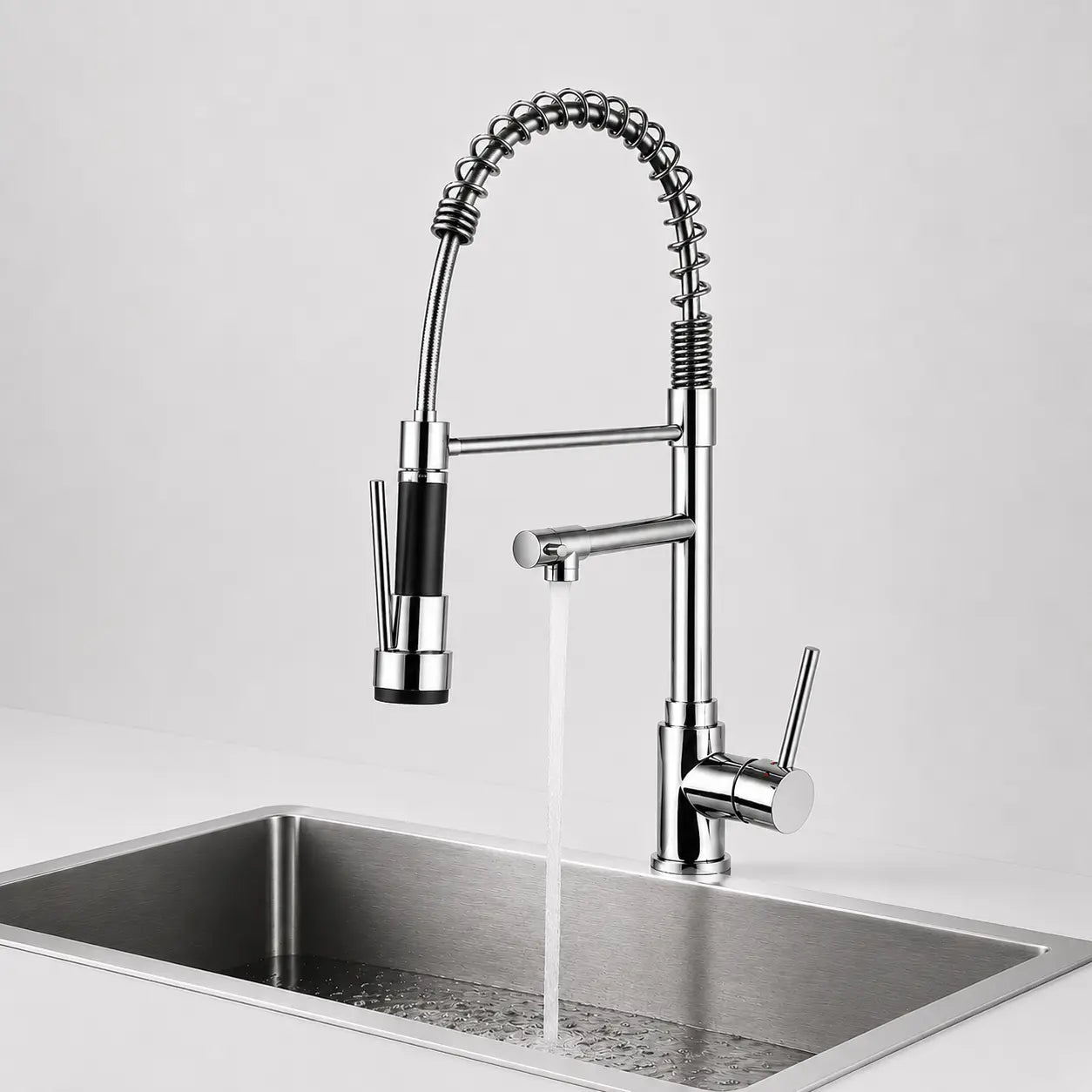Robinet de cuisine chromé avec douchette extractible à ressort et bec moderne au-dessus d’un évier inox Image