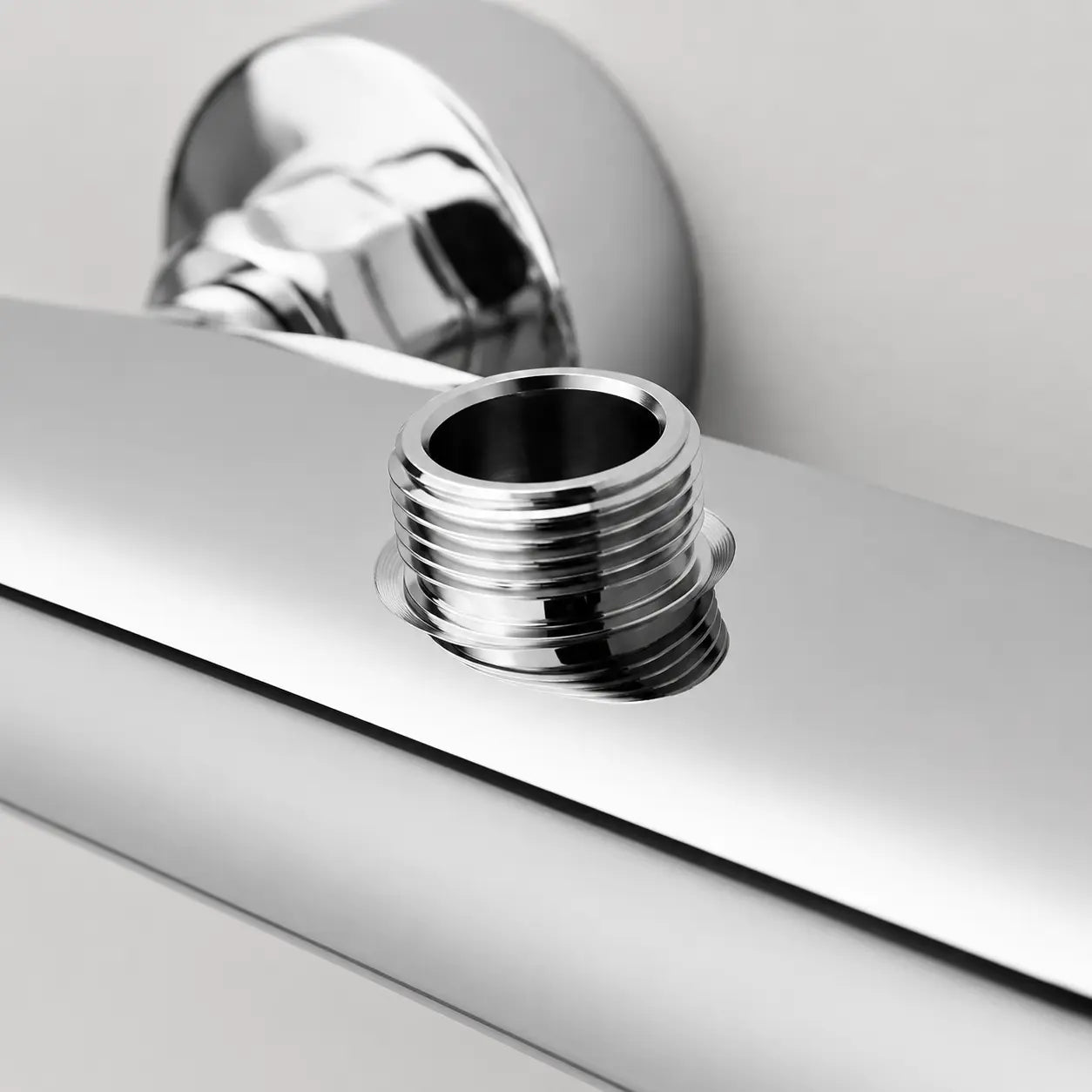 Gros plan sur la sortie filetée chromée du mitigeur thermostatique, conçue pour raccorder un flexible de douche. Image