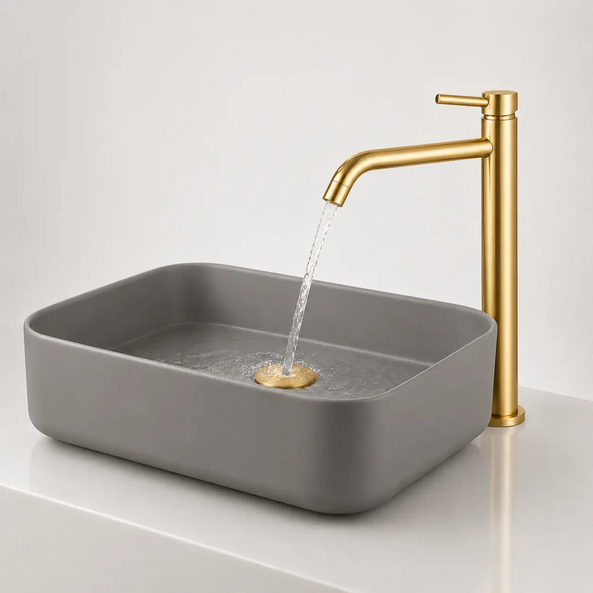 Robinet mitigeur haut en or brossé avec bec incurvé, installé sur vasque moderne grise avec écoulement d’eau