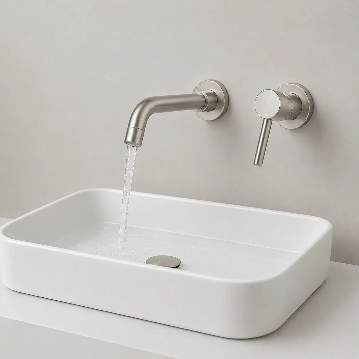 Robinet mural gris brossé avec écoulement d’eau dans une vasque blanche au design moderne et minimaliste