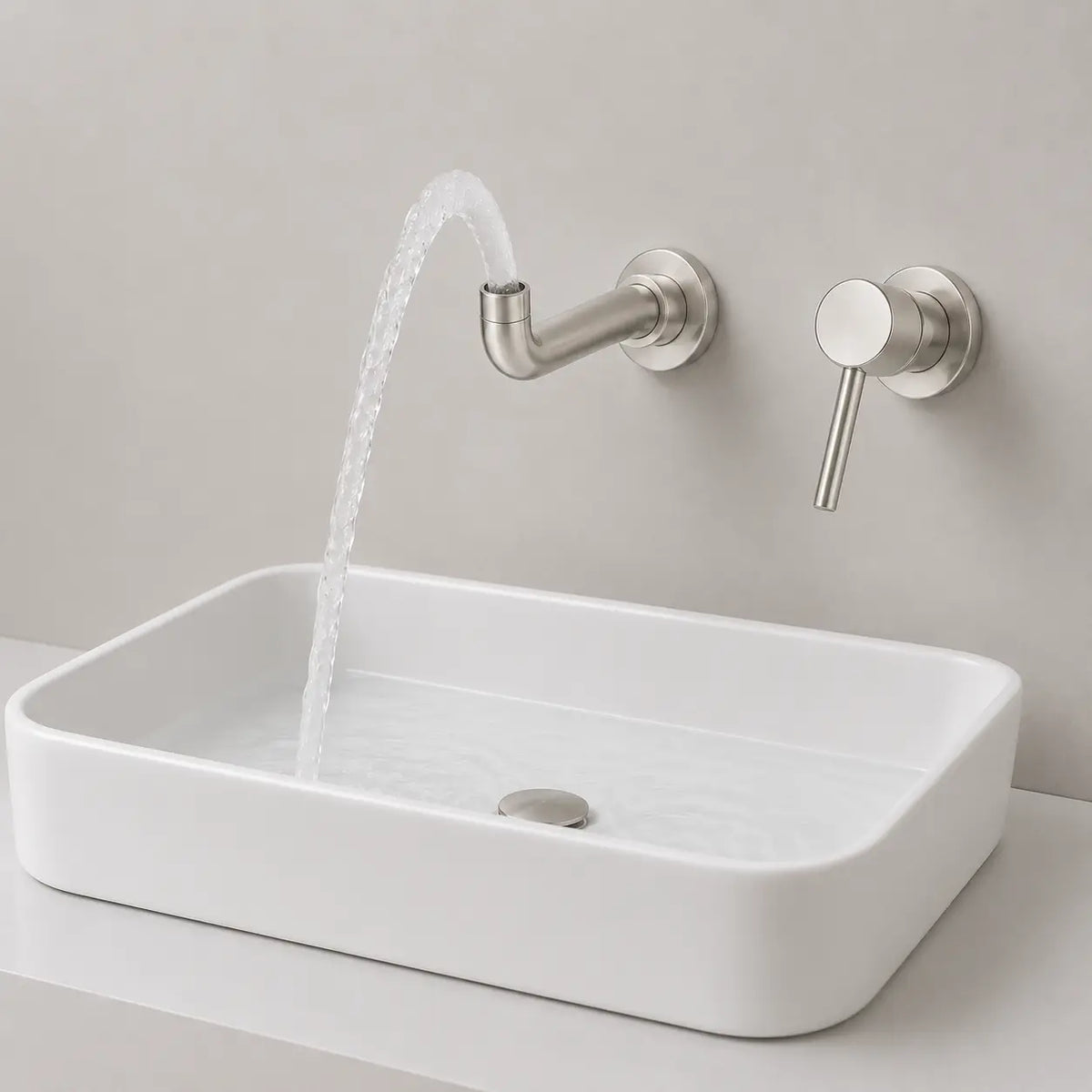 Robinet mural gris brossé avec jet d’eau courbé au-dessus d’une vasque blanche au style contemporain
