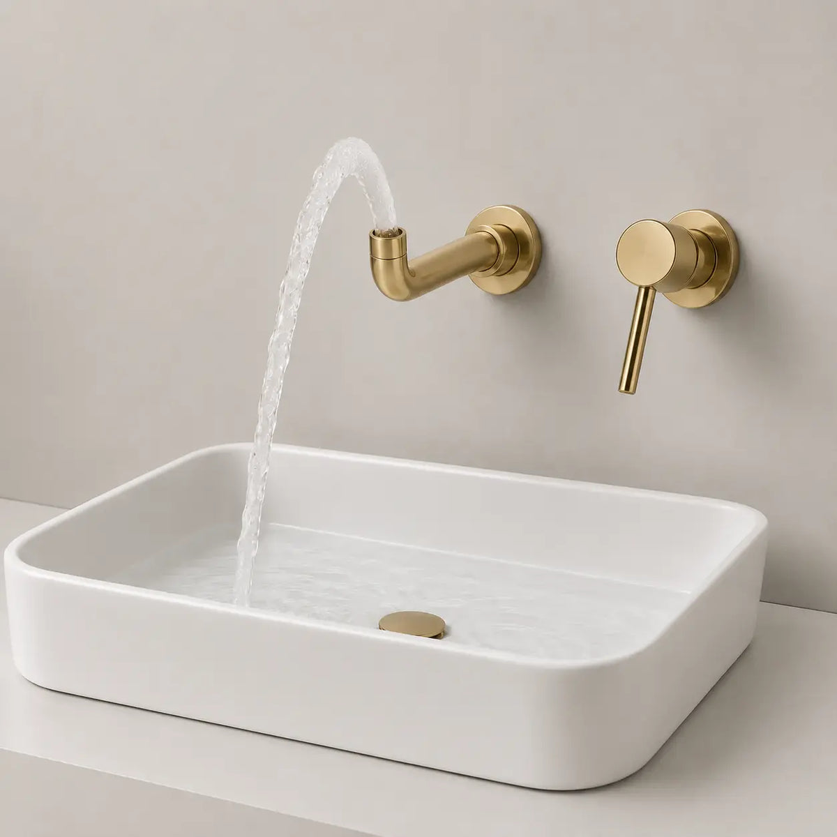 Robinet mural encastré or brossé avec jet d’eau courbé au-dessus d’une vasque blanche contemporaine