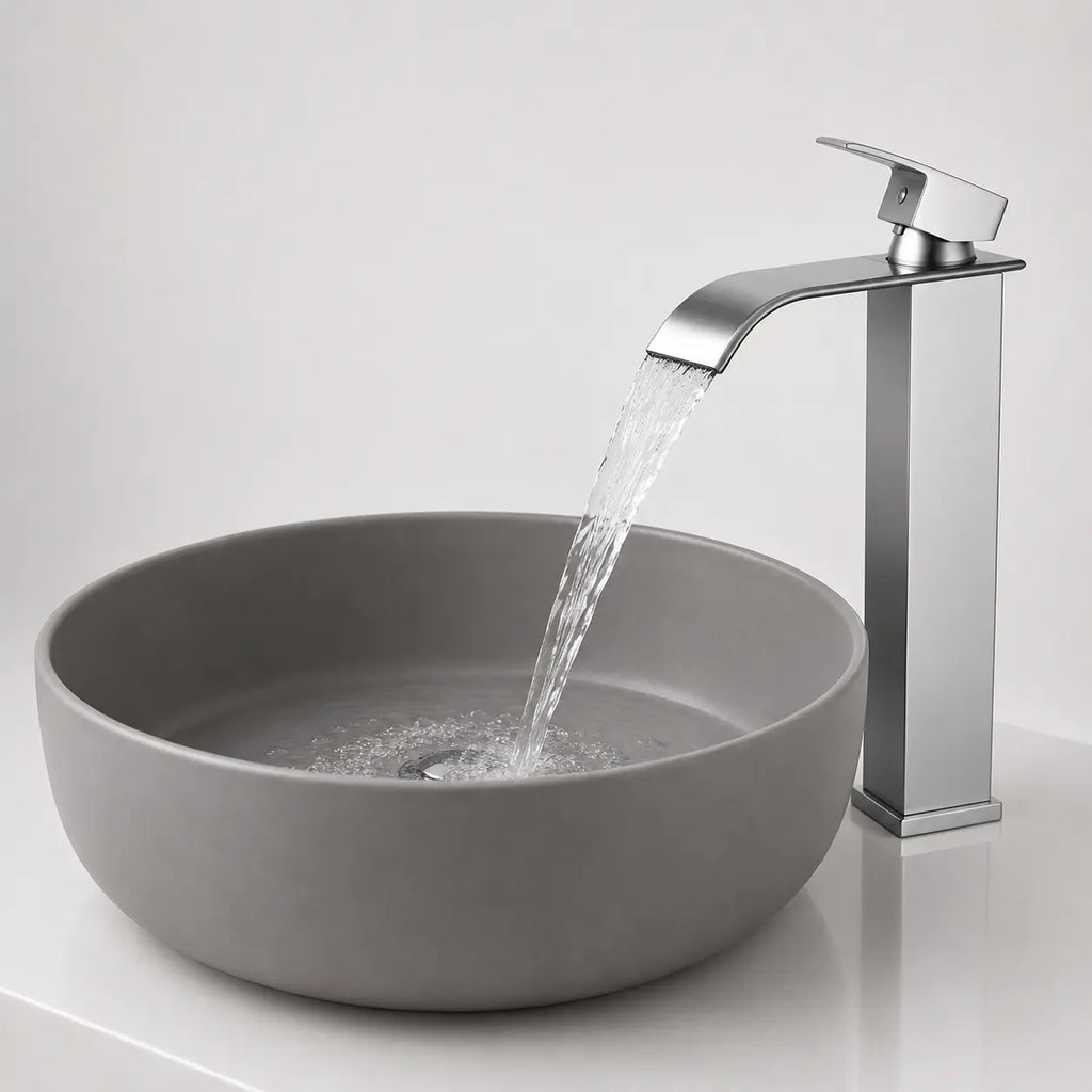 Robinet de vasque moderne chromé avec écoulement cascade en fonctionnement au-dessus d’une vasque ronde contemporaine