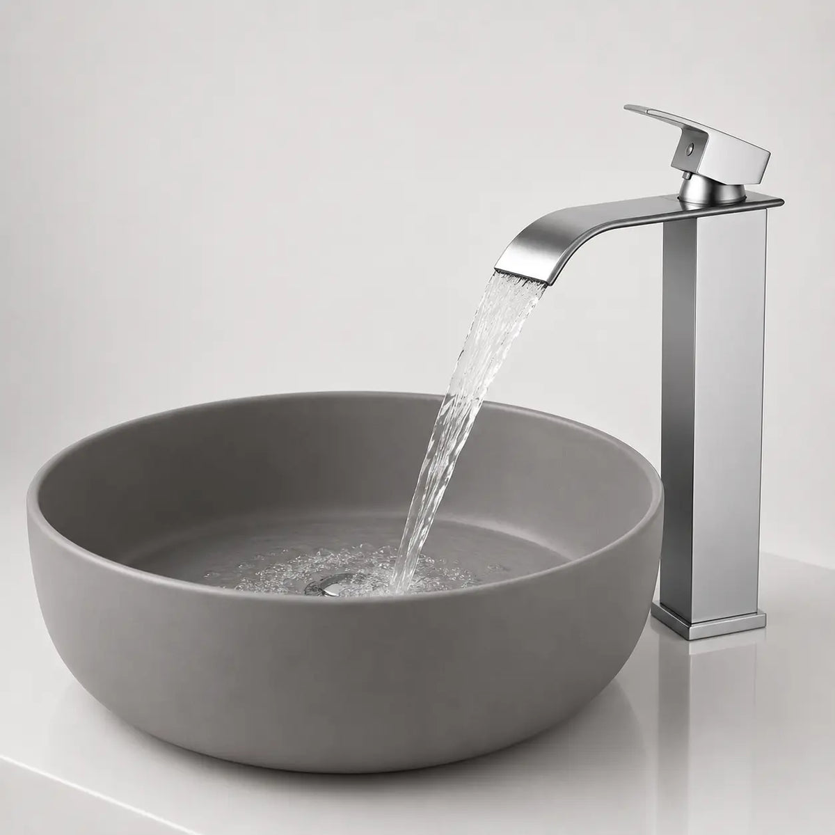 Robinet de vasque moderne chromé avec écoulement cascade en fonctionnement au-dessus d’une vasque ronde contemporaine