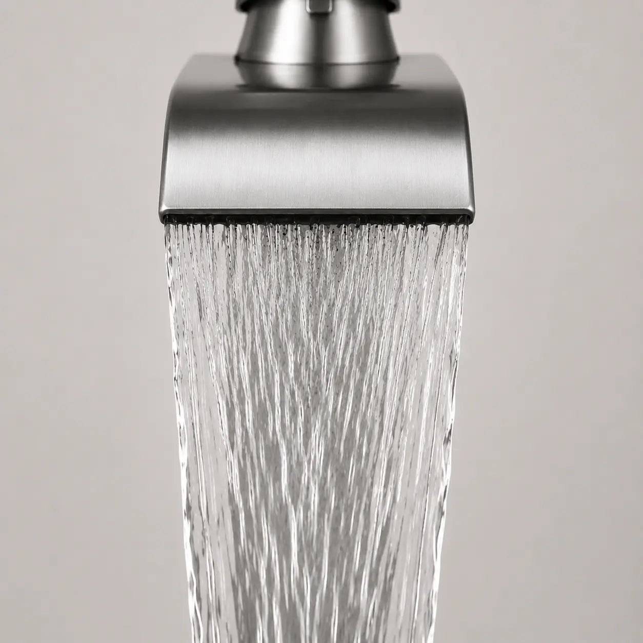 Gros plan sur un robinet de vasque chromé avec jet cascade fluide, mettant en valeur l’écoulement large et le design moderne Image