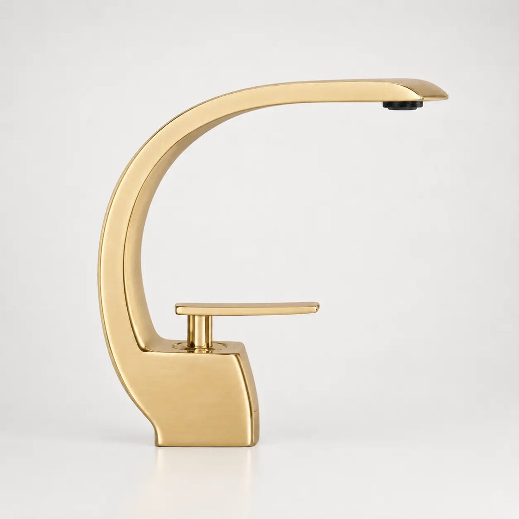 Robinet de lavabo design en or brossé, silhouette arquée élégante avec bec haut et commande monocommande moderne.