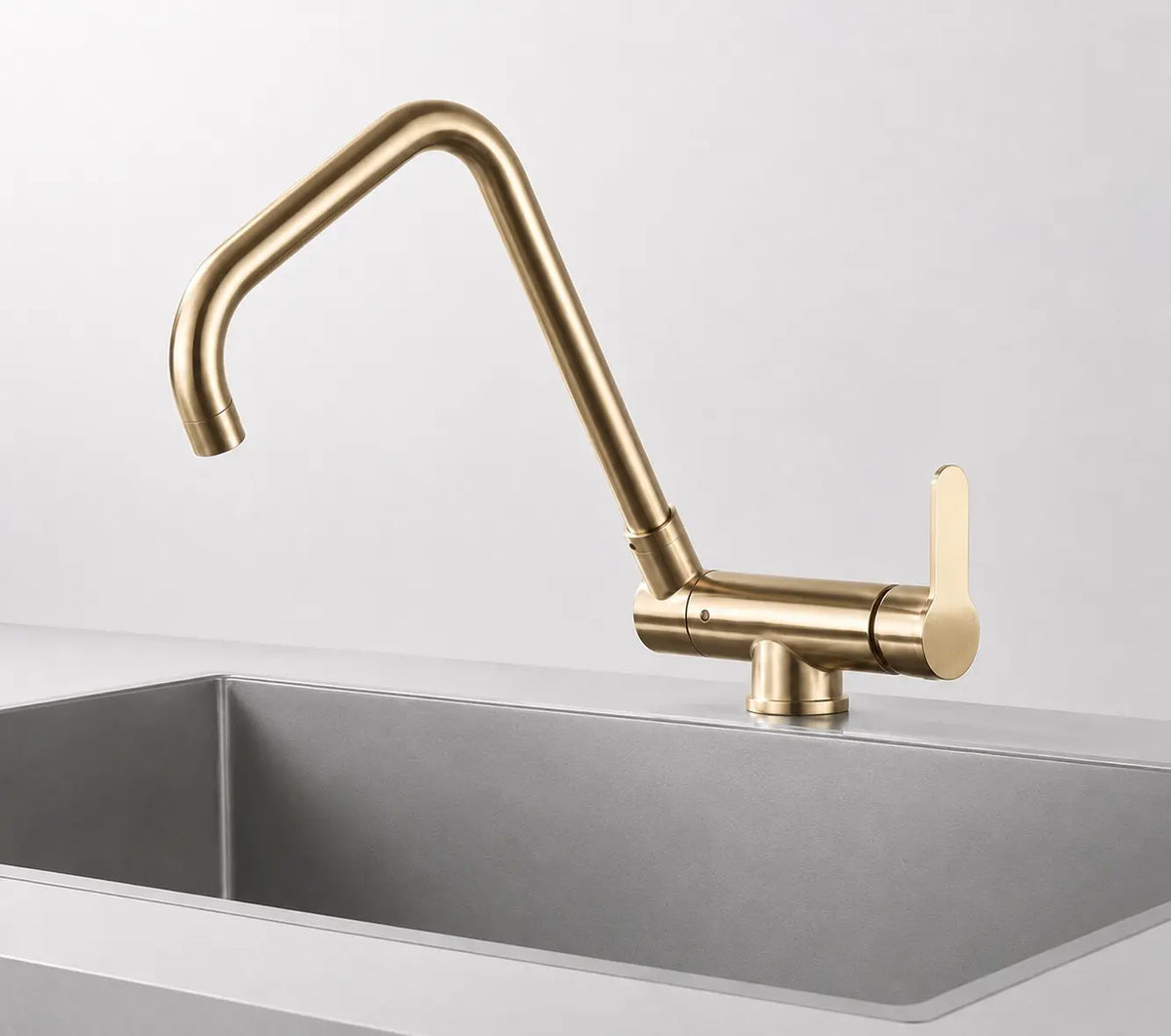 Robinet de cuisine doré brossé avec bec orientable angulaire et poignée latérale, installé sur évier moderne